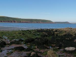 a beach with a body of water and rocks at Le Chalet - 2 Bedroom Chalet House sleeps 3 in Pembrokeshire