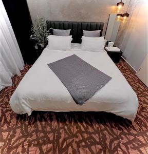 duże białe łóżko z czarnym zagłówkiem i białymi poduszkami w obiekcie Troika Avenue Kota Bharu by The Stay Homestay w mieście Kota Bharu