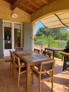 - une table et des chaises sur une terrasse avec un parasol dans l'établissement Villa provençale entre Cévennes et Provence avec une grande piscine et un terrain de pétanque, à Martignargues