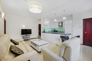 a living room with white furniture and a kitchen at Luxury Mayflower Apartment, Central City Centre, Newly Refurbished in Plymouth