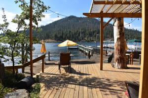 eine Holzterrasse mit Tisch und Sonnenschirm in der Unterkunft Charming 1927 Lake Front Home - Hargrave in Bass Lake