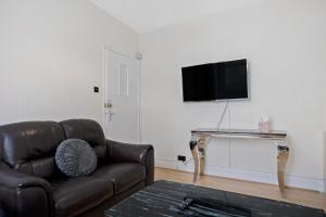 een woonkamer met een bank en een televisie aan de muur bij The Smeaton Apartment, Central City Centre in Plymouth