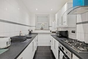 a white kitchen with a sink and a stove at The Smeaton Apartment, Central City Centre in Plymouth