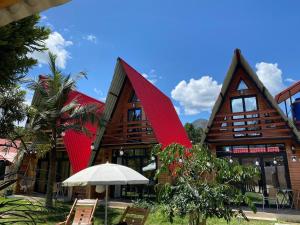 a building with red roofs with chairs and an umbrella at Estancia Chontabamba - Cabañas, Departamento y Habitaciones in Oxapampa