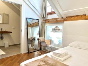 1 dormitorio con espejo, 1 cama y 1 silla en Historic Rooms and Apartments in the City Centre of Bolzano en Bolzano