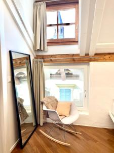 a mirror and a chair in a room with a window at Historic Rooms and Apartments in the City Centre of Bolzano in Bolzano