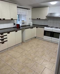 a kitchen with white cabinets and a tile floor at Chata VISTA Strážné in Strážné