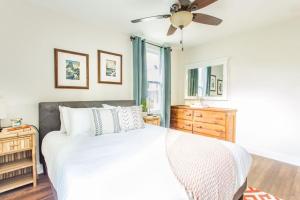 Un dormitorio con una cama blanca y un ventilador de techo. en Open and Comfy home near Downtown-Folly Beach, en Charleston