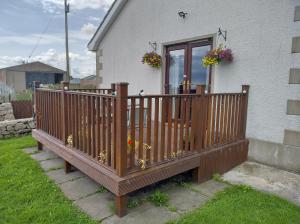 a wooden deck in front of a house with flowers at Carrick Cove Deluxe Room with private decking in Annalong