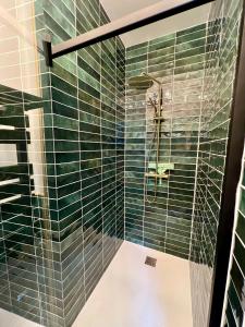 a shower with green glass tiles in a bathroom at Appartement de luxe avec fresque, hyper centre et parking sûre in Fontainebleau +21 photos