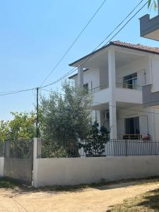 ein weißes Haus mit einem Zaun davor in der Unterkunft Anushe's apartament in Pogradec