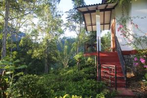 a house with a staircase leading up to a balcony at Rivinu Holiday Resort in Ella