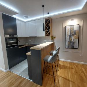 a kitchen with white cabinets and a bar with a stool at Apartment Mb lux 2 in Bijeljina