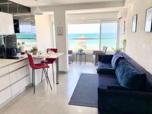 een woonkamer met een bank en een tafel en een keuken bij Seaside cozy apartment in Haifa