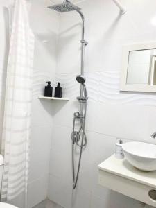 a white bathroom with a shower and a sink at Seaside cozy apartment in Haifa