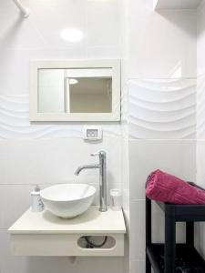 La salle de bains est pourvue d'un lavabo blanc et d'un miroir. dans l'établissement Seaside cozy apartment, à Haïfa