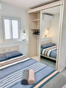 ein kleines Schlafzimmer mit 2 Betten und einem Spiegel in der Unterkunft Seaside cozy apartment in Haifa