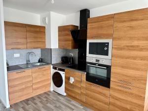 a kitchen with wooden cabinets and a sink and a microwave at Agréable 2 pièces avec balcon et Parking transports by immo kit bnb in Sarcelles