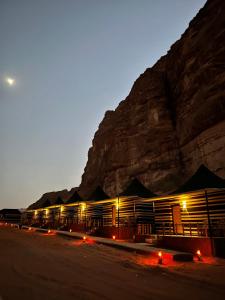 a building in front of a mountain at night at STARDUSt CAMP in Wadi Rum