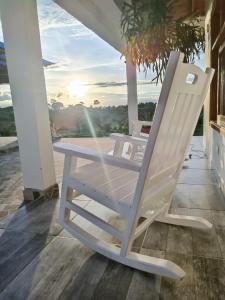 a white rocking chair on a porch with the sunset at El Encanto de las Aguas in Necoclí