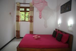 a bedroom with a pink bed with a pink stuffed animal on it at Rivinu Holiday Resort in Ella