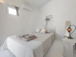 a white bedroom with two beds and a window at Καμάρα (Kamara) cave rooms in Triovasálos