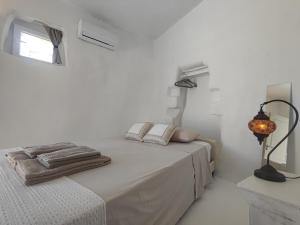 a white bedroom with a bed with towels on it at Καμάρα (Kamara) cave rooms in Triovasálos