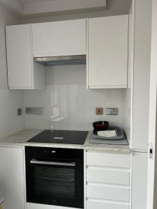 a kitchen with a black oven and white cabinets at Victoria in London