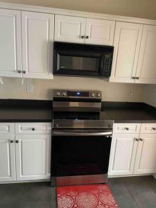 a kitchen with white cabinets and a black oven and microwave at Prattville Delight*Jacuzzi Tub*+Central Location* in Prattville