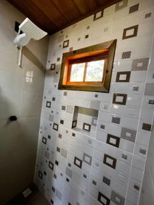 een badkamer met een raam en een witte tegelmuur bij Pousada Sossego do Tocantins in Lajeado