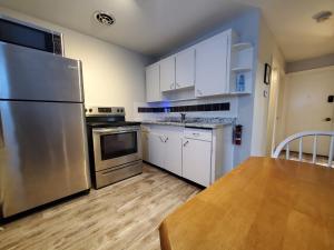 una cocina con nevera de acero inoxidable y armarios blancos en Modern Private 1BR Apt. w/Free Prkg + Fast Wi-Fi, en Sault Ste. Marie