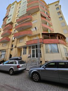 two cars parked in front of a tall building at Drion Apartment with lake view in Pogradec