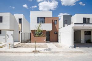 a house with white facades and a tree in the courtyard at Estrena casa a minutos del aeropuerto in Monterrey