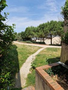 un chemin dans un champ planté d'arbres en arrière-plan dans l'établissement Appartement aux Minimes Magnifique Vue Mer au pied de la Plage 50m2-2ch., à La Rochelle