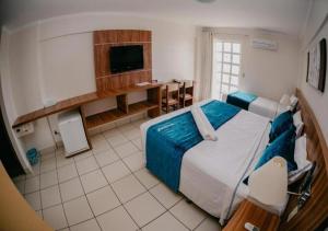 a hotel room with a bed and a tv at DiRoma Exclusive in Caldas Novas