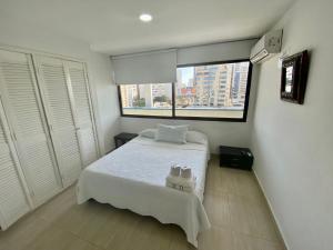 ein Schlafzimmer mit einem weißen Bett und einem Fenster in der Unterkunft Apartamentos En Edificio Portofino ICDI in Cartagena de Indias