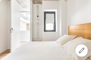 Un dormitorio blanco con una gran cama blanca y una ventana en CASA CASCO HISTÓRICO, en Sevilla