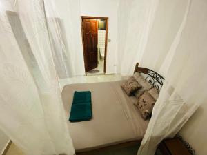 een bed in een kamer met witte gordijnen bij Ngor Rooftop Terrace & Apartment in Dakar