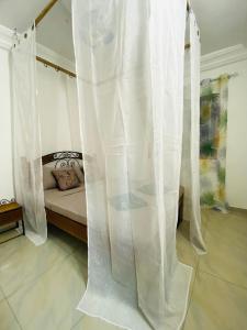 een bed met witte gordijnen in een kamer bij Ngor Rooftop Terrace & Apartment in Dakar