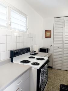 eine weiße Küche mit einem Herd und einem Fenster in der Unterkunft Elegancia Acogedora: Tu Rincón en San Juan in San Juan