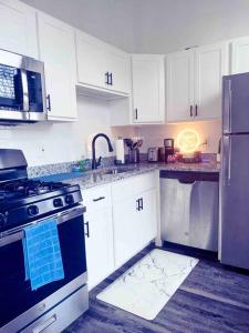 a kitchen with white cabinets and a stove and refrigerator at 2Br Unit W/ Cinema Room in Nulu in Louisville