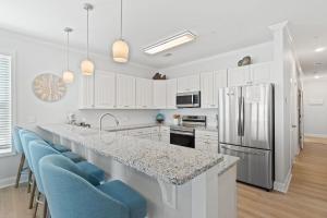 a kitchen with white cabinets and a counter with blue chairs at Pescador Landing 6A in Pensacola