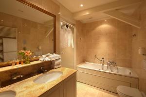 a bathroom with a sink and a tub and a toilet at Relais & Châteaux Hotel Heritage in Bruges