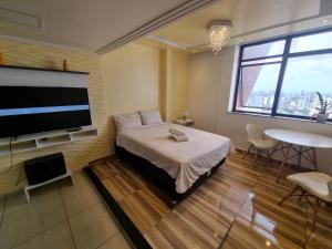 a bedroom with a bed and a flat screen tv at DerSalvador Sol Victoria Marina Studios in Salvador