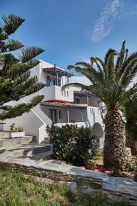 a white house with a palm tree in front of it at Irene Studios in Agios Petros
