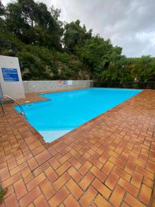 a large blue swimming pool with a brick floor at T2 dans résidence calme avec piscine in Le Gosier