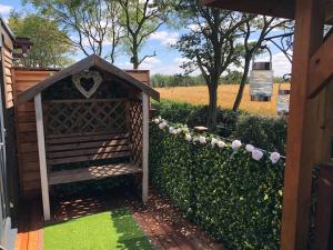 a garden with a wooden gate and a hedge with flowers at Couple’s Lodge With Hot Tub in Lincolnshire