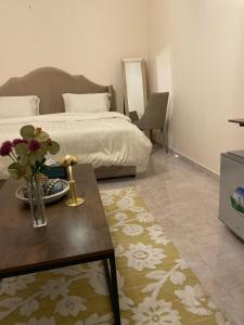 a bedroom with a bed and a table with flowers on it at استديو عائلي بمدخل خاص ودخول ذاتي in Riyadh Al Khabra