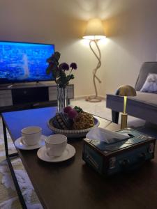 a living room with a coffee table with two cups and flowers at استديو عائلي بمدخل خاص ودخول ذاتي in Riyadh Al Khabra