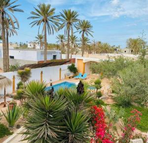 a resort with a swimming pool and palm trees at Mille & une nuit in Al Maqārisah